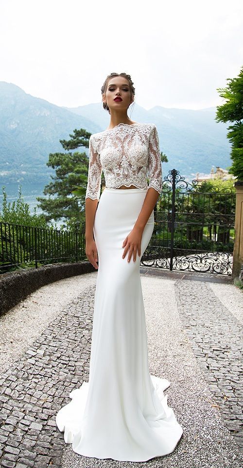 a woman in a white dress is standing on a cobblestone road and posing for the camera