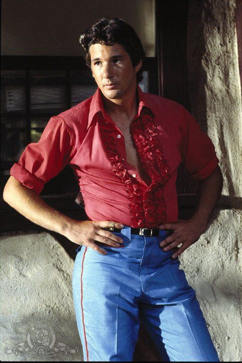 an image of a man in red shirt and jeans posing for the camera with his hands on his hips