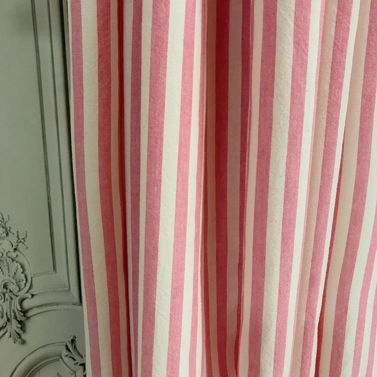 a pink and white striped curtain hanging on the side of a door with an ornate frame