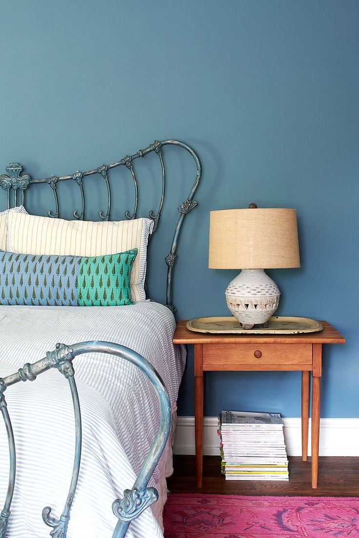 a bedroom with blue walls and a metal headboard on the bed, next to a pink rug