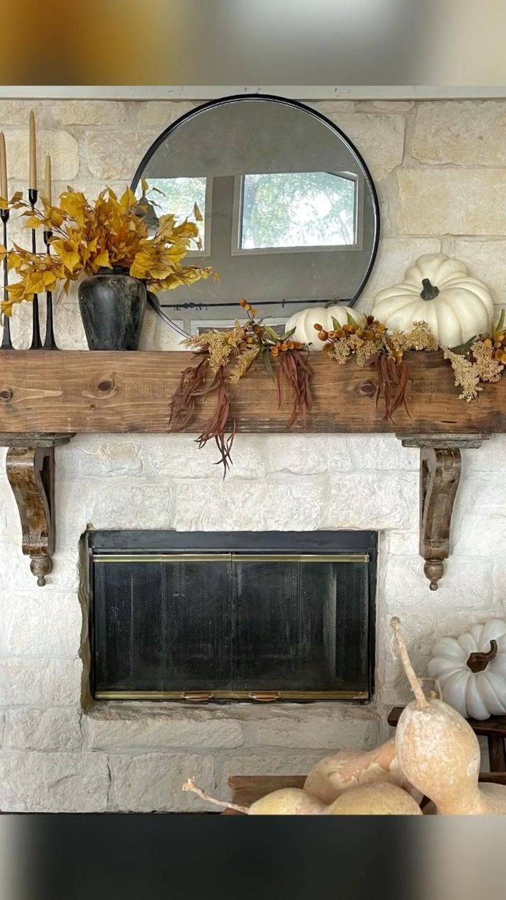 a fireplace mantle with pumpkins, gourds and candles