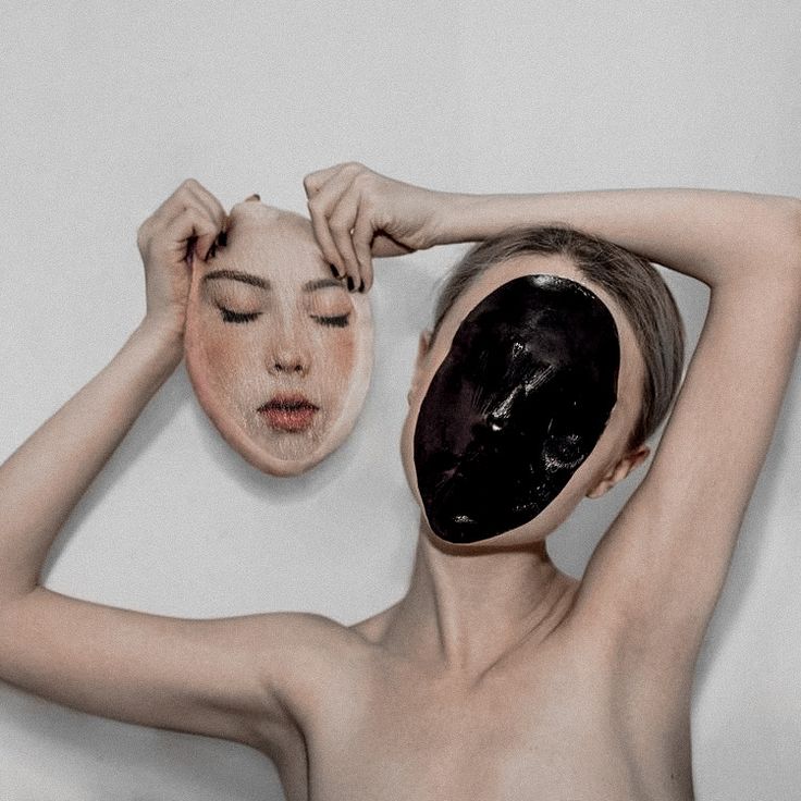 a woman holding up a mask to her face