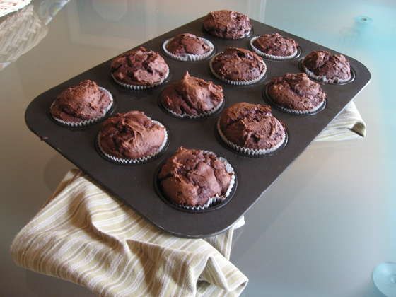 chocolate cupcakes sitting on top of a baking tray with muffin tins