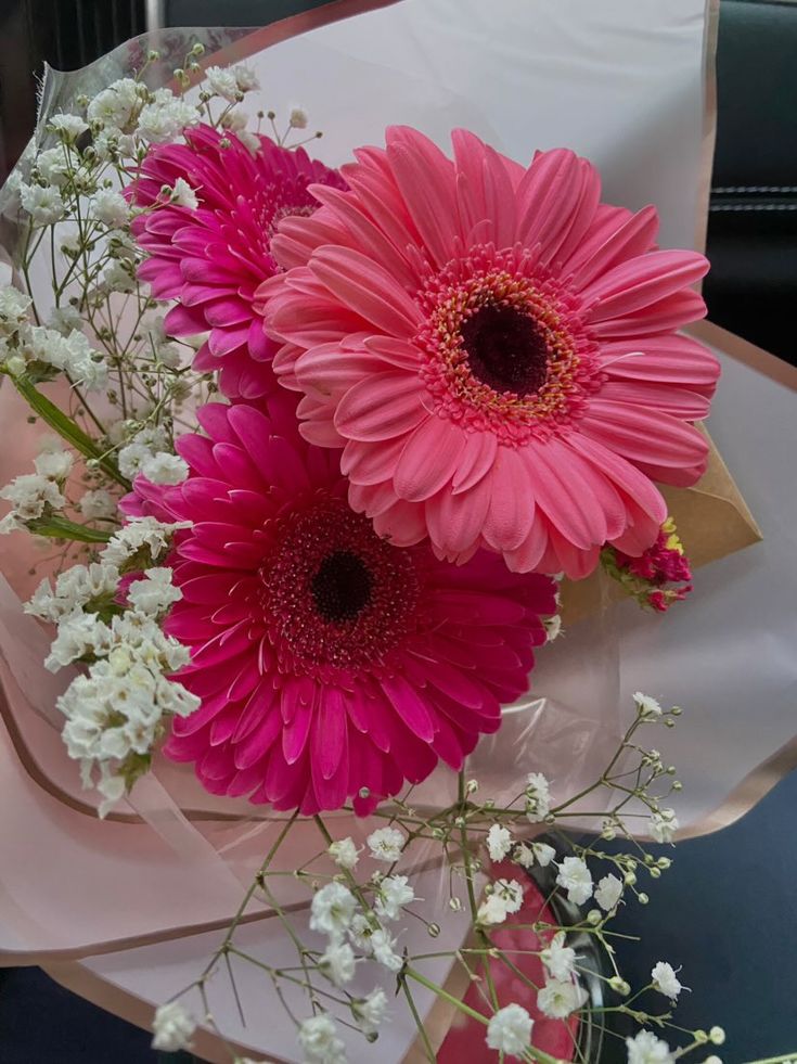 three pink and white flowers are in a bouquet