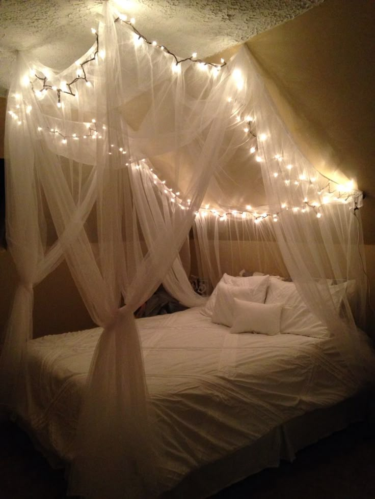 a bed with white sheets and lights on it