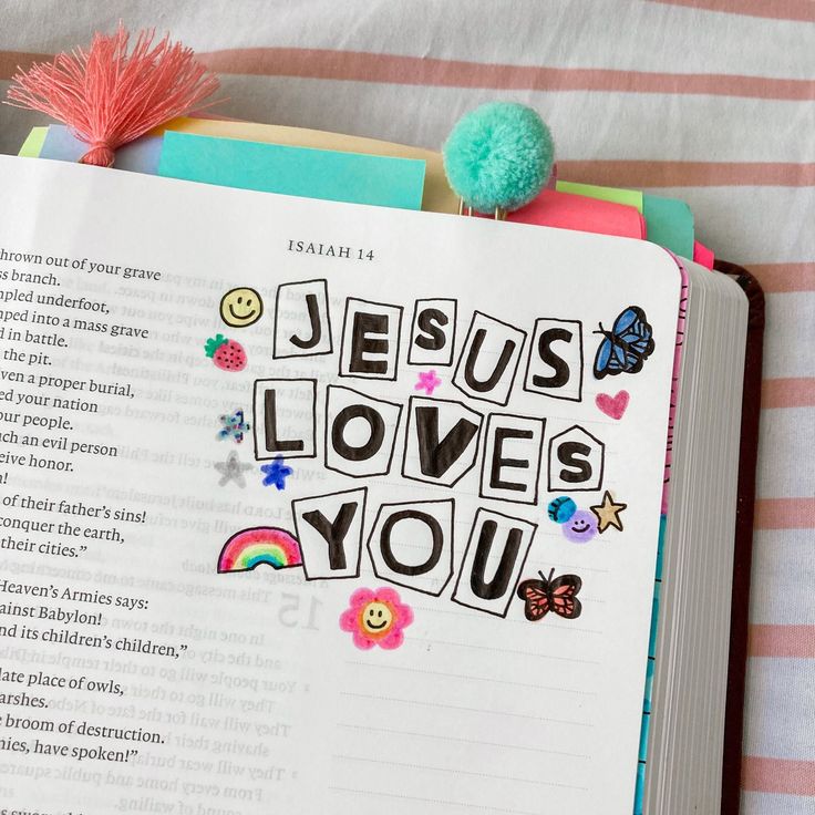 an open bible with the words jesus loves you written in colorful letters and flowers on it