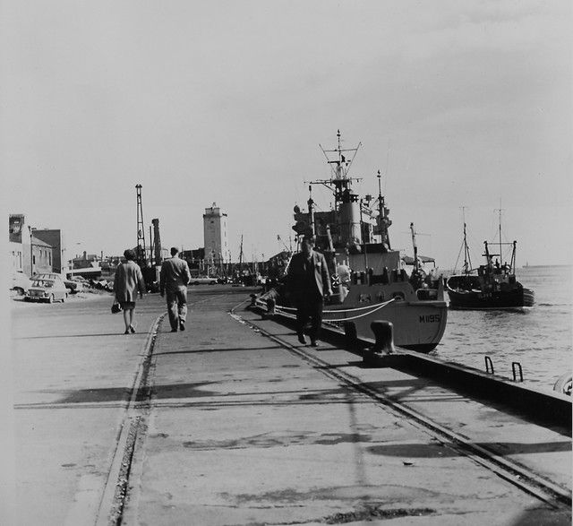 black and white photograph of people walking on the dock