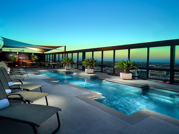 an outdoor swimming pool with lounge chairs overlooking the city