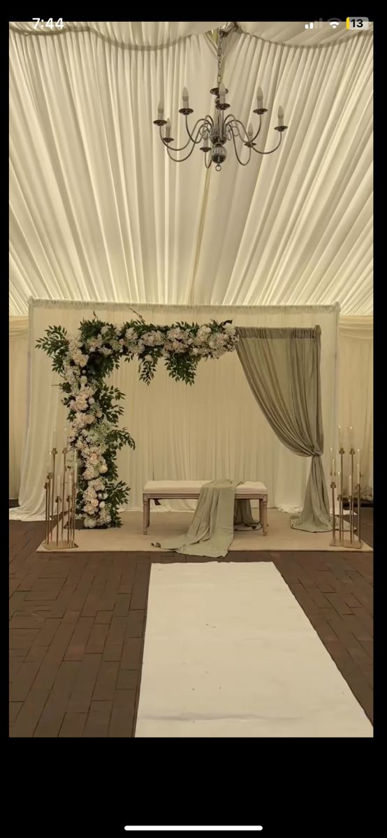 a wedding ceremony setup with white drapes and greenery