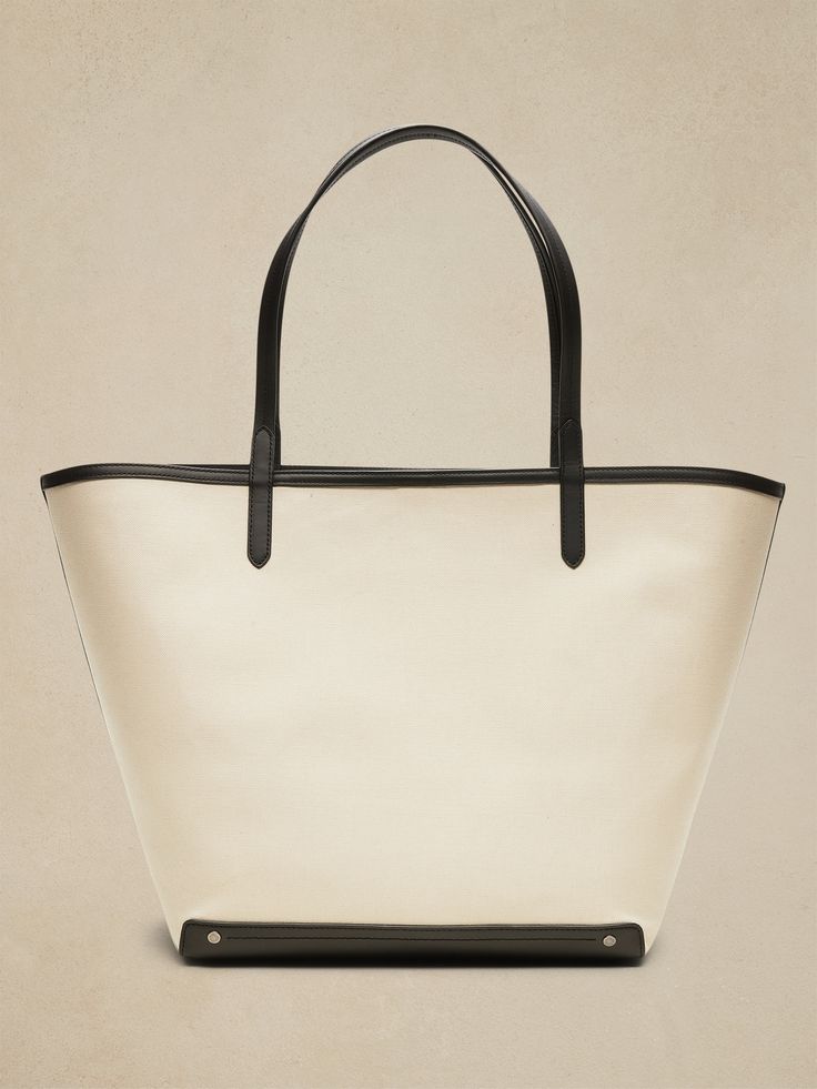 An elegant companion to everyday style, this classic tote goes anywhere with ease with spacious storage, sturdy leather trim, and a snap closure.  Sturdy leather handles.  Open top with snap closure.  Height: 16" (41cm) Width: 25" (63cm) Depth: 8" (2 14th Anniversary, Canvas Leather Tote, Canvas Leather Bag, Mommy Style, Leather Handles, Open Top, Canvas Leather, Everyday Style, Leather Trim