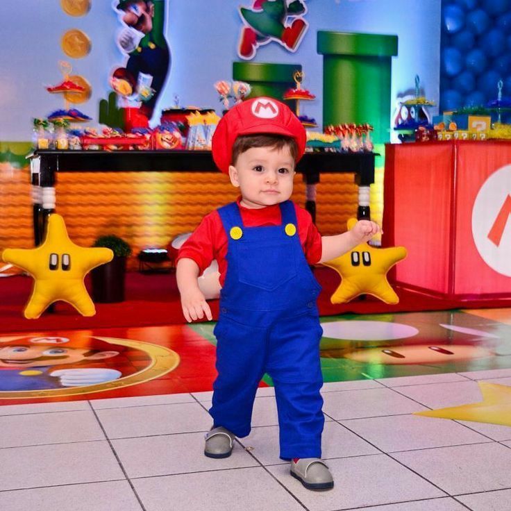 a little boy dressed up as mario in front of a playroom with toys on the floor