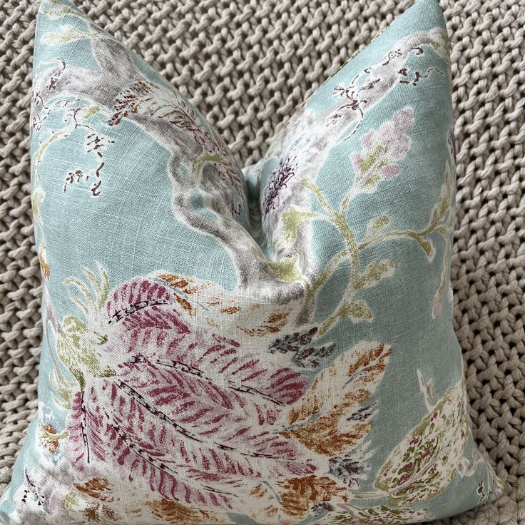 a blue pillow with a floral pattern on it sitting on top of a wicker chair