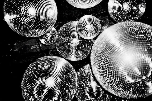 many shiny disco balls are arranged in a black and white photo with the lights turned on