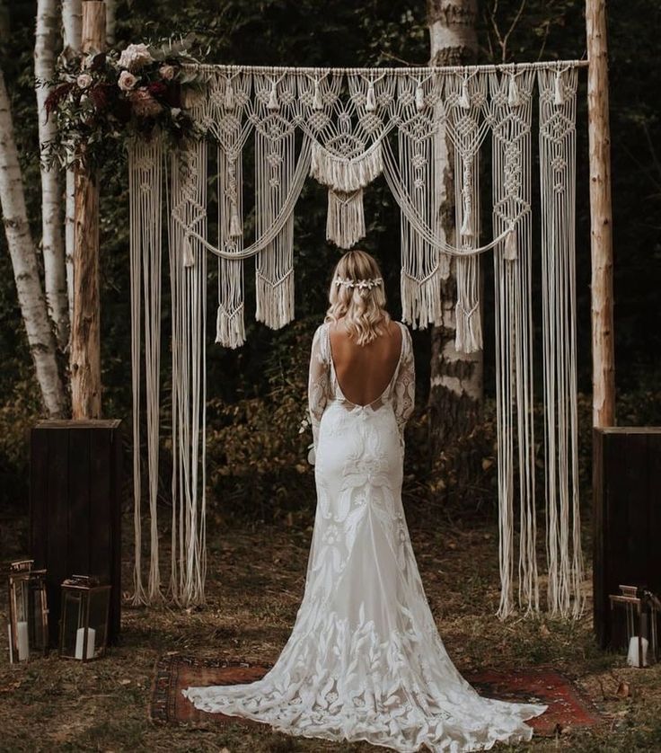 the back of a bride's dress standing in front of an outdoor wedding ceremony