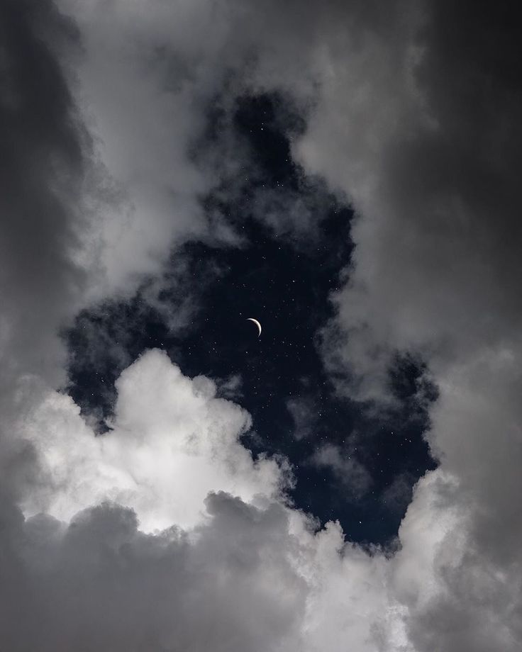 the moon is seen through some clouds in this black and white photo