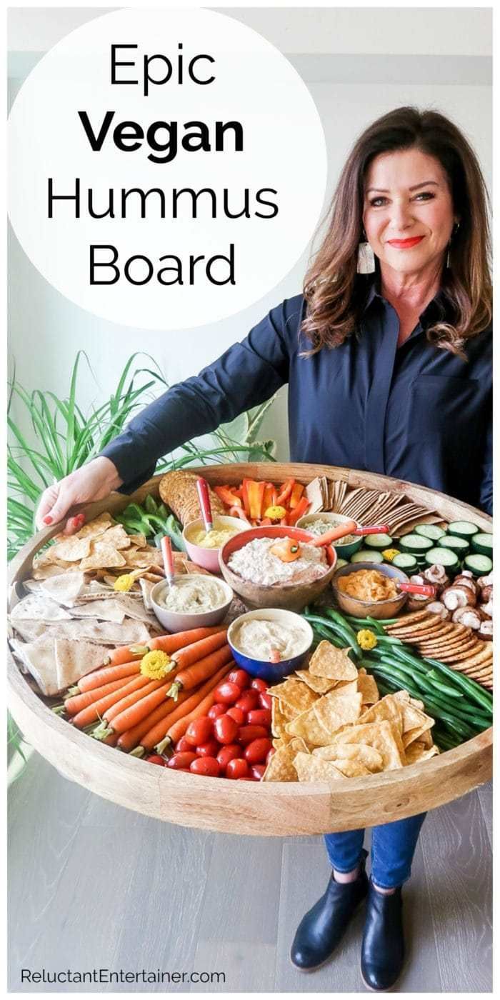 a woman standing in front of a large platter filled with vegetables and dips