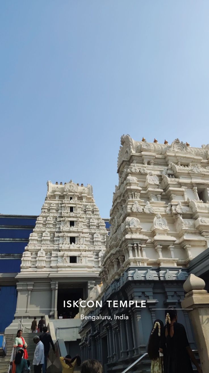 people are walking up and down the stairs in front of an ornate building with statues on it