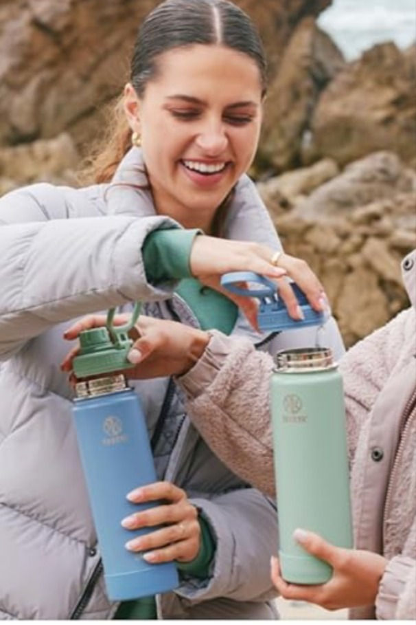 two women standing next to each other holding water bottles