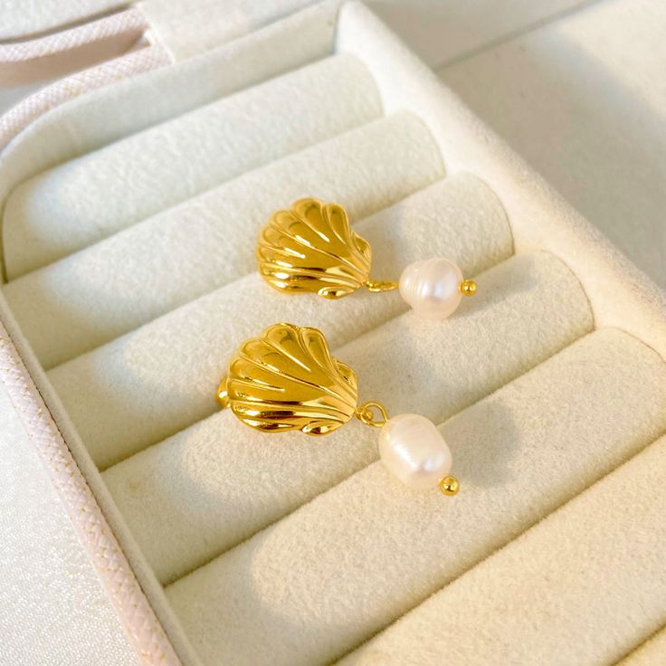 Experience the beauty of the ocean with our stunning 18K Seashell Freshwater Pearl Earrings. These earrings feature delicate seashell pendants and lustrous freshwater pearls, creating a fashionable yet timeless look. Crafted with high-quality stainless steel, these earrings are perfect for any beach lover or fashion enthusiast. Elevate your style with our 18K Seashell Freshwater Pearl Earrings today! Pearl Drop Shell As A Gift, Elegant Shell Drop Earrings As Gift, Elegant Drop Shell Earrings As A Gift, Elegant Shell Drop Earrings For Gift, Pearl Earrings With Shell Shape For Gift, Elegant Shell Pearl Earrings For Gift, Gold Shell Pearl Earrings As Gift, Elegant Gold Shell As Gift, Elegant Shell Dangle Jewelry