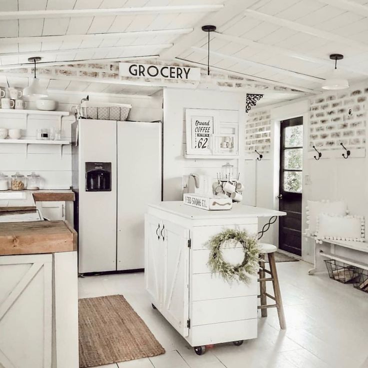 a kitchen with white walls and floors has a small island in the middle