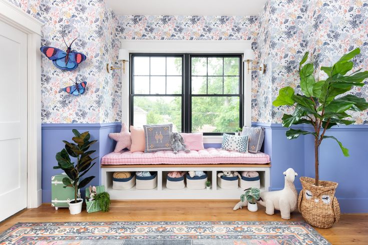 a living room with blue walls and floral wallpaper on the walls, a bench in front of a window