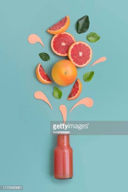 grapefruit, oranges and green leaves falling out of a bottle