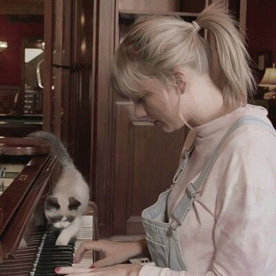 a woman is playing the piano with her cat