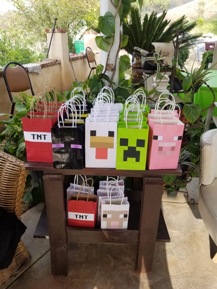 several bags are sitting on a table in front of some plants and potted plants