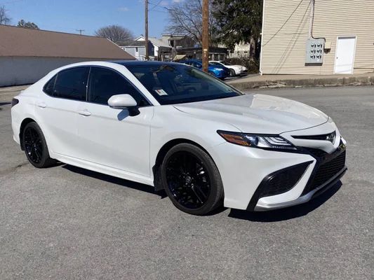 a white toyota camry parked in a parking lot next to a building and trees