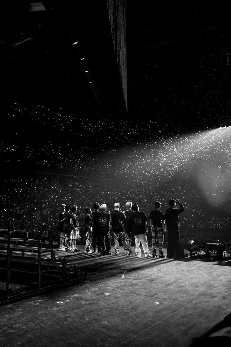 a group of people standing on top of a stage in front of a crowd at a concert