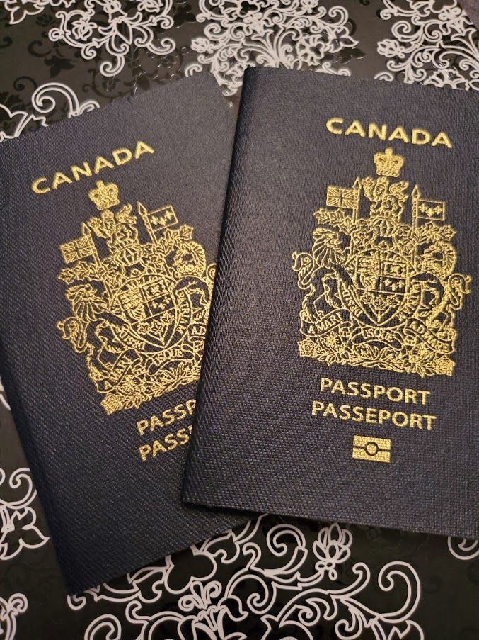 two canadian passports sitting next to each other on top of a lace covered tablecloth