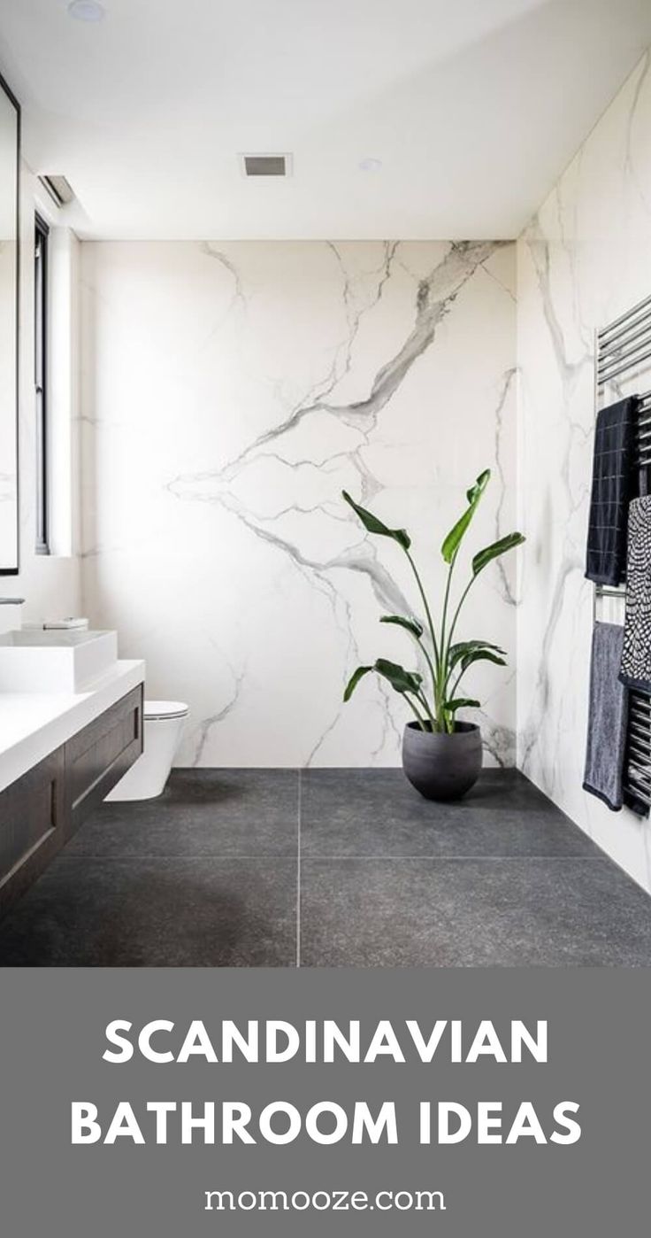 a bathroom with white marble walls and flooring next to a plant in a black pot