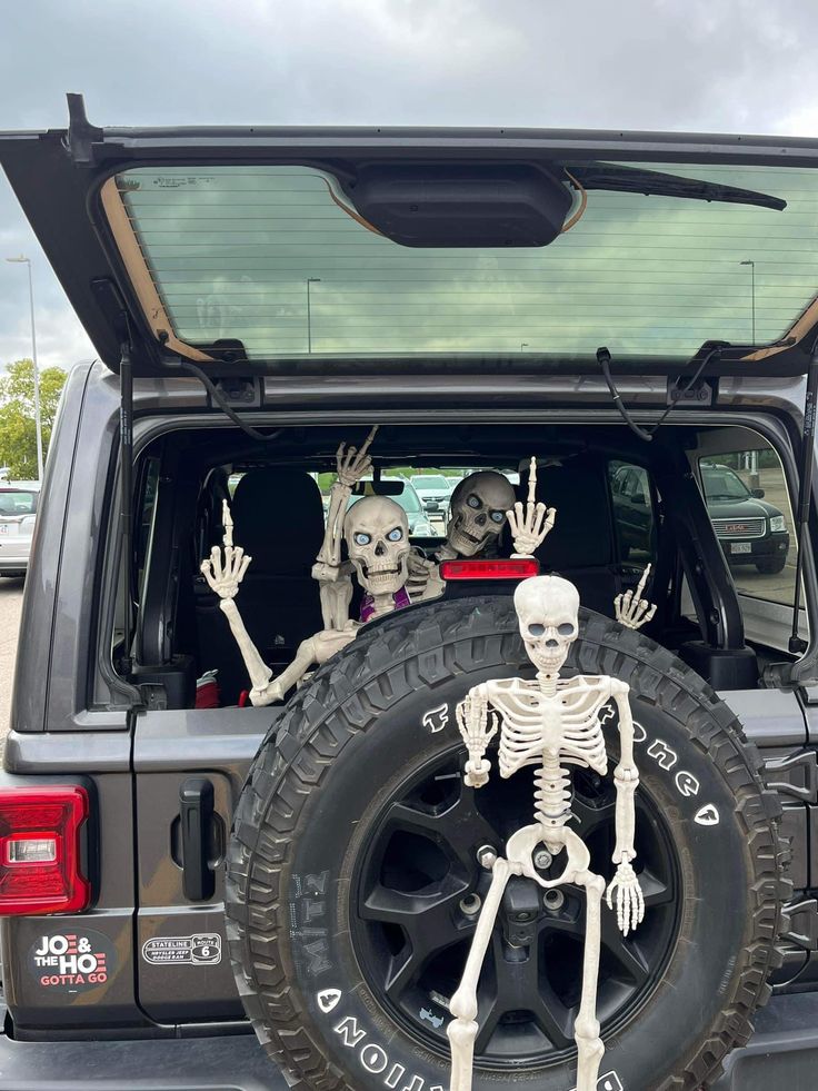 two skeletons sitting in the back of a jeep