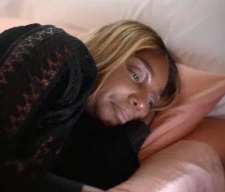 a woman laying on top of a bed next to pillows