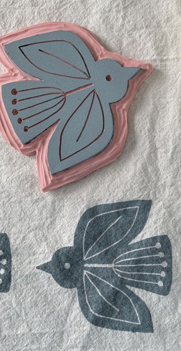 a bird shaped cookie sitting on top of a white sheet covered in blue and pink icing