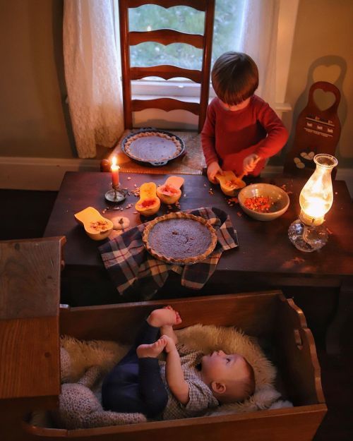 two young children sitting at a table with food and candles in front of their faces