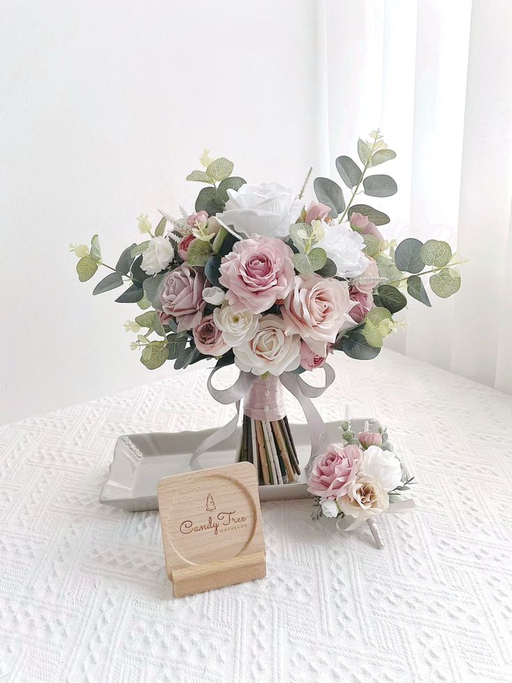 a bouquet of flowers sitting on top of a table next to a wooden box with a card