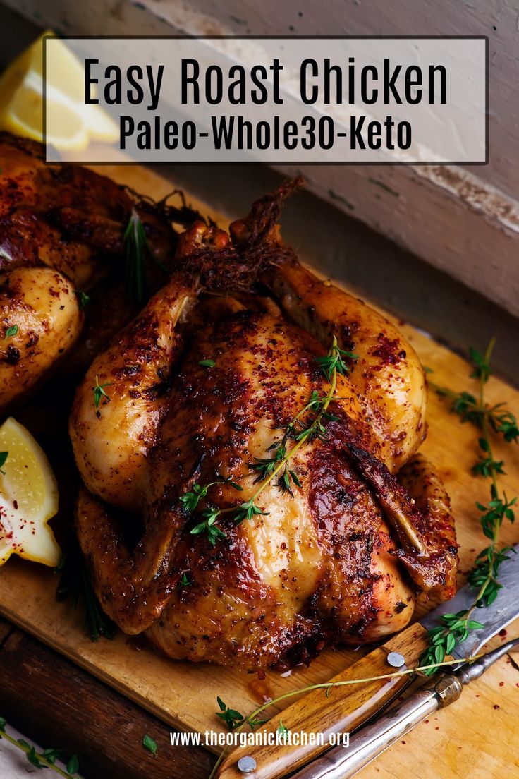 a close up of a chicken on a cutting board with lemons and parsley