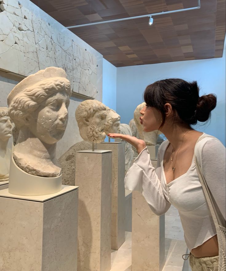 a woman pointing at statues in a museum