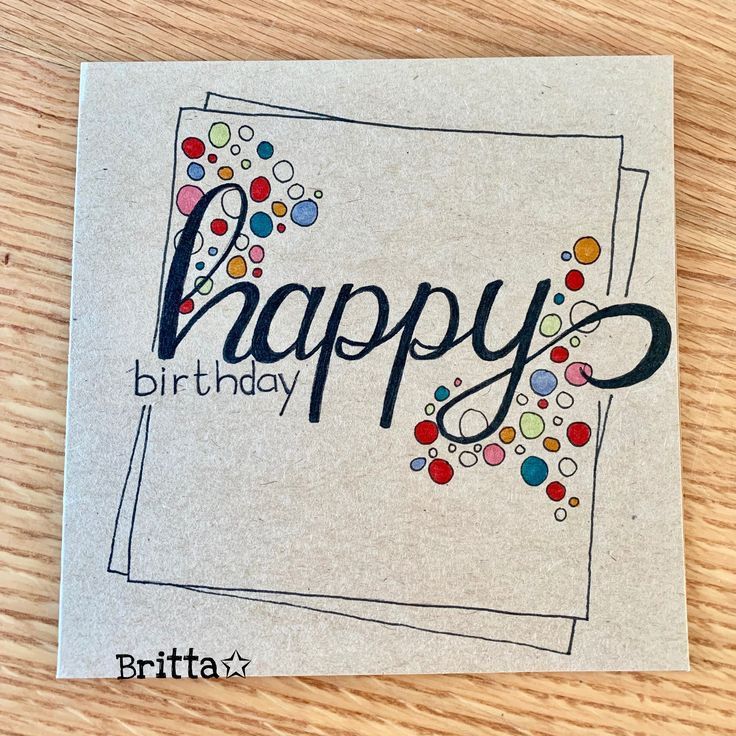 a happy birthday card with confetti and bubbles on the front, sitting on a wooden surface