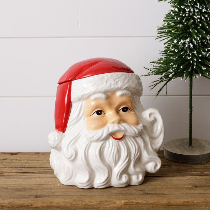 a ceramic santa clause head next to a small christmas tree