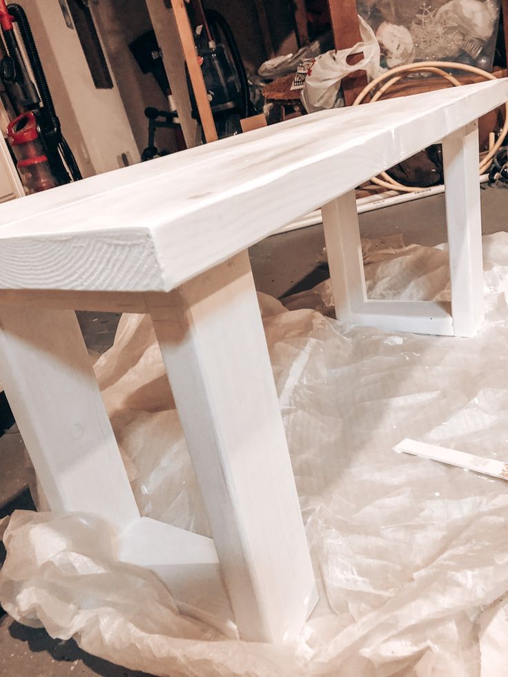 a white wooden bench sitting on top of a pile of plastic wrap next to a pair of scissors