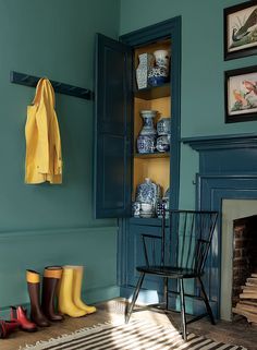 a living room with blue walls and yellow accessories on the fireplace mantel, painted in farrow teal