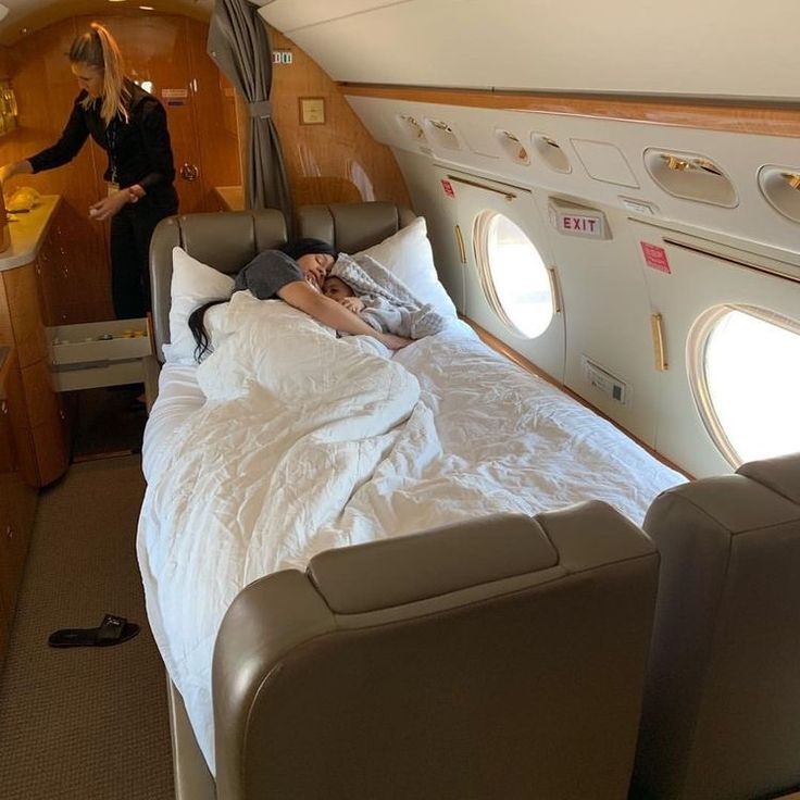 a woman standing next to a bed in an airplane