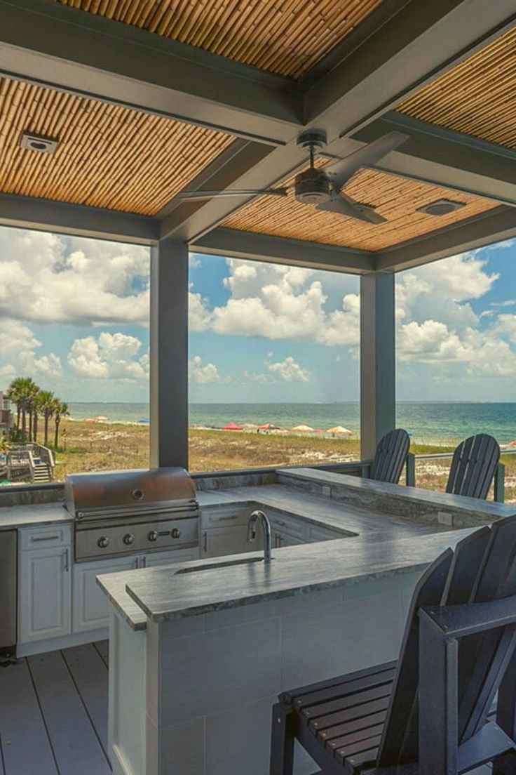 an outdoor kitchen and grill area overlooking the ocean