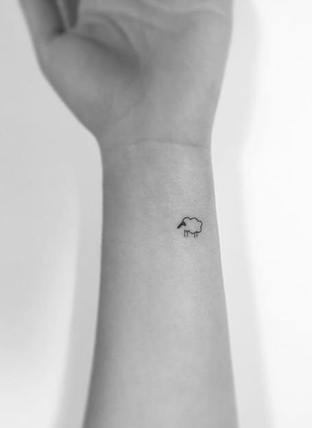 a black and white photo of a hand with a small sheep tattoo on the wrist