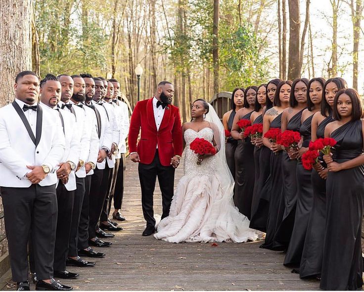 a group of people standing next to each other in front of a bride and groom