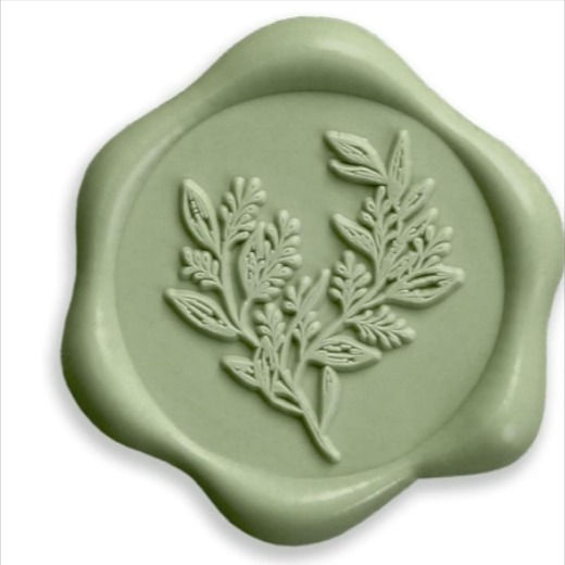 a green wax stamp with leaves on the front and bottom, sitting on top of a white background