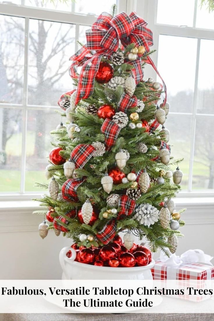 a christmas tree decorated with red, white and silver ornaments in front of a window