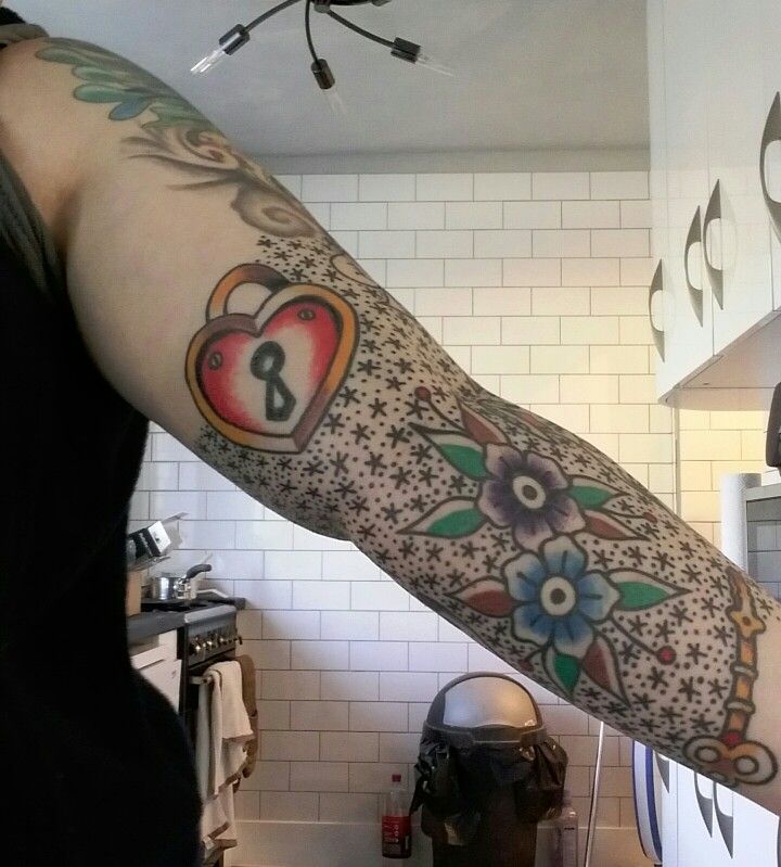 a woman with a tattoo on her arm holding up a clock and flowered heart